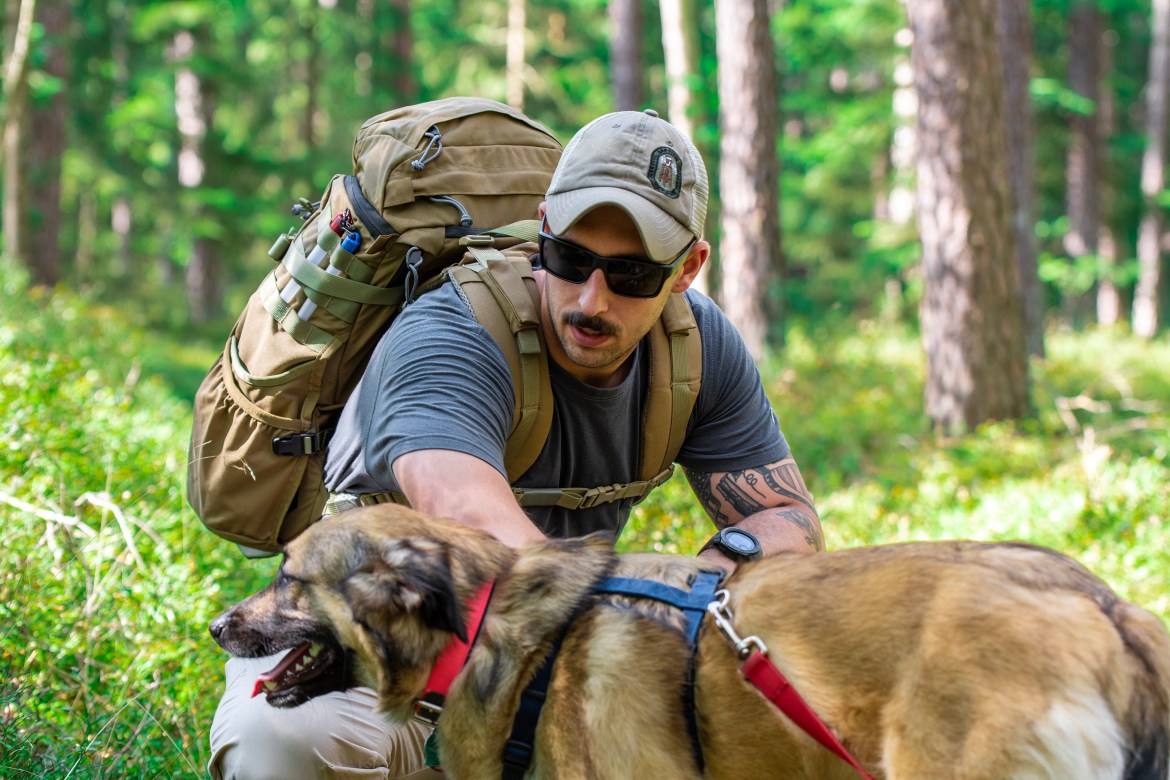 Mystery Ranch 3dap early model pals webbing passthrough pocket design side view harness on body in forest with dog